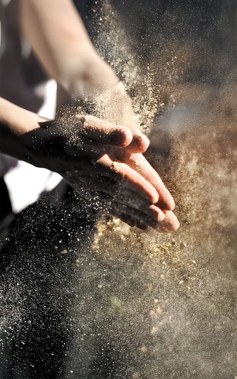 Hände, die Mehl in die Luft klatschen.